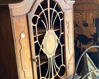 Antique wooden cabinet featuring an arched top and decorative leaded glass door with geometric and oval motifs. Warm wood finish with period detailing and visible patina consistent with age. An elegant storage or display piece ideal for traditional interiors, collectors, or restoration projects. All items sold as-is.