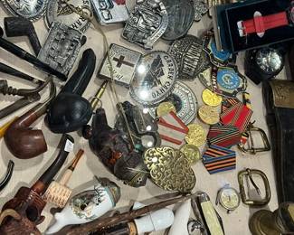 Dense assortment of vintage and antique smalls featuring badges, medals, belt buckles, coins, pins, smoking accessories, tools, and mixed metal objects. Includes military and fraternal insignia alongside decorative and utilitarian pieces. A true treasure-hunt grouping ideal for collectors, dealers, and resellers. Condition varies; all items sold as-is.