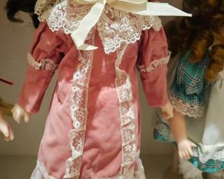 Collectible porcelain doll with pink dress and bonnet.