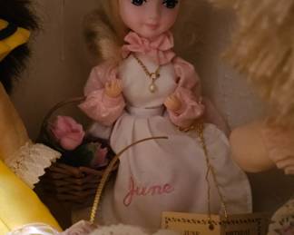 A vintage fashion doll with blonde hair, wearing a straw hat and pink polka-dot outfit.