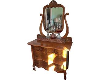 Antique tiger oak serpentine dresser with carved mirror. Late 19th century.