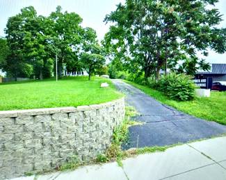 The driveway to the property is to the right of the stone wall
