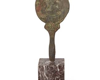 3328
A Greek bronze hand mirror
Circa 100-600 AD or later
Likely assembled, with a figure depicted in relief to one side, above a handle with scrolls at the juncture, set into a later square rouge marble base
Paddle: 8.875" H x 4.125" W; Base: 3.125" H x 3" W x 3" D
Estimate: $300 - $500