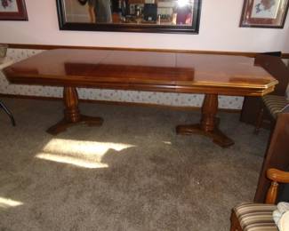 This pedestal dining room table is shown with two 18" leaves with a total length of 8'; the table also comes with 6 chairs and a small matching buffet.