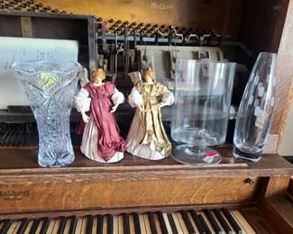 The image displays a collection of vintage and decorative items, including a Meldorf organ, two figurines, and three glass vases. 
The figurines resemble the style of Precious Moments or other collectible porcelain figurines