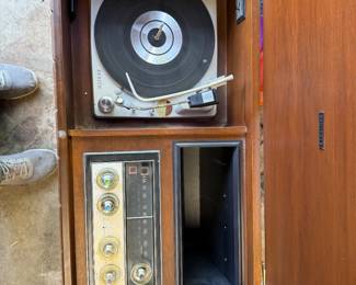 This is a mid-century modern Zenith solid-state stereo console in a walnut finish. 
The console features a built-in record player and AM/FM radio. 
It has louvered doors that conceal the speakers and record storage compartments. 
Many Zenith consoles from this era, including models like the MN2604, are sought after by collectors for their stylish appearance and quality components. 
The record player often features the Micro-Touch 2G tonearm, known for its light tracking force. 
