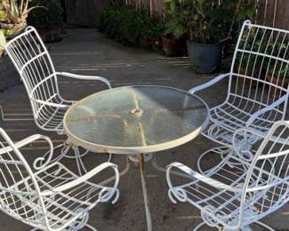 This is a vintage Homecrest mid-century modern metal wire patio dining set, featuring four swivel rocking chairs and a glass-top table. 