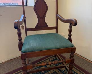Vintage Queen Anne style brown wooden armchair with a green upholstered seat cushion