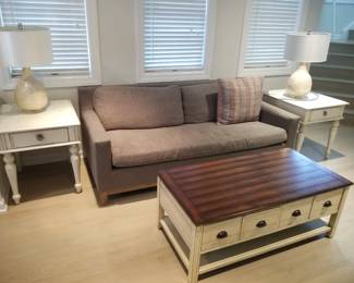 Neutral sleeper sofa; end tables by Tommy Bahama; table lamps; coffee table on wheels