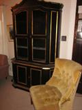Upholstered chair with fringe, black/gold display cabinet.