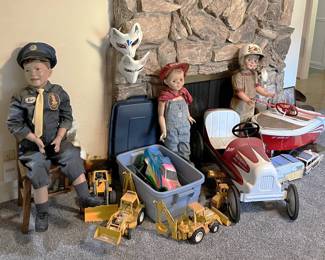 In this photo you can see a collection of vintage toys, including a couple of pedal cars, a pair of fox masks, and Tonka (or similar) construction toys.
