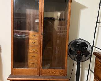 This armoire is a bit unusual in that it features glass doors. Of course, if you need a standing fan, that is here, too. Partially shown is a quilt rack.