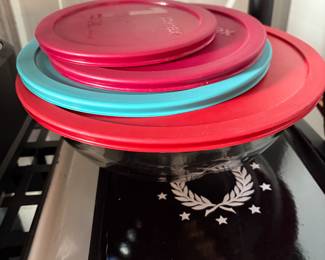 Four different size Pyrex bowls with lids for each bowl. All four are stacked inside each other.