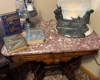 Eastlake Carved Table with Marble Top with Scene in Action Motion Lamp and antique cruet set and vintage books