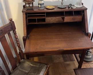 Antique oak drop-front secretary desk with matching period wooden chair.