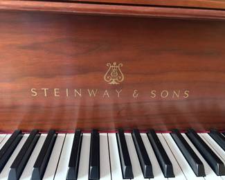 Very well-maintained Steinway & Sons baby grand piano in a warm wood finish, complete with matching bench.
