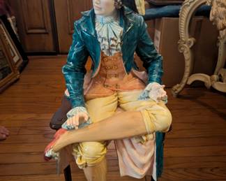 Porcelain figure that sits on a chair or a flat surface