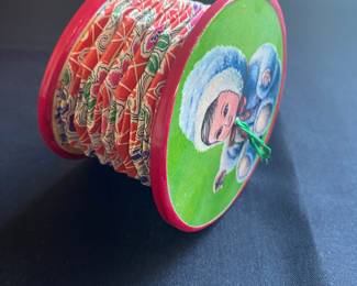 a squeeze box this small, handheld toy features an accordion-style design with pleated paper or fabric in the center and circular cardboard ends.