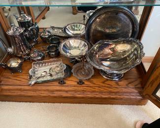 silver-plated serving dishes and tea set items.