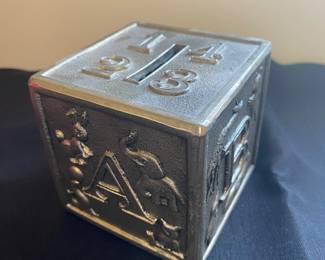 a vintage silver-plated ABC block coin bank, often made by brands like Raimond or Leonard.