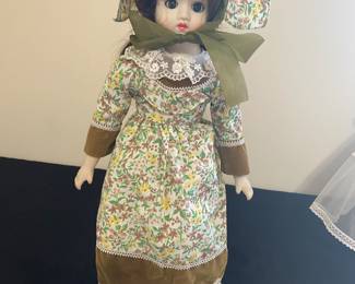 a vintage or collectible porcelain doll, possibly from the Albert Price collection, dressed in a calico-style dress and bonnet.