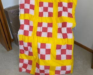 handmade quilt featuring a checkerboard pattern in yellow, white, and red floral fabric.