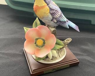 Northern Parula warbler perched on a branch with a pink and white flower.