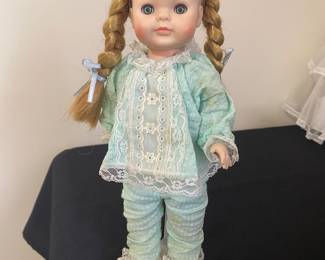 vintage doll she has blonde hair styled in pigtails with blue bows and is wearing a light green pajama set with white lace trim. possibly Vogue "Ginny"