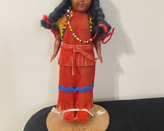 vintage Native American souvenir doll, specifically identified as being "MADE BY The Cherokees" on its heart-shaped wooden stand. These types of dolls were popular as souvenirs in the 1960's