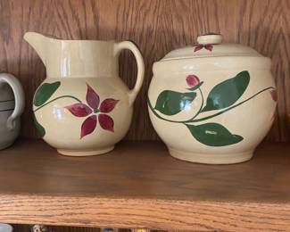 vintage Watt Pottery items in the highly collectible Starflower pattern. a pitcher and a covered cookie jar or canister, feature a hand-painted design of red, five-petal flowers and green leaves on a creamy yellow base.