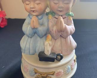 a vintage ceramic musical figurine featuring a boy and girl praying.