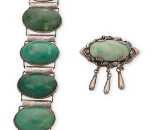 195
A group of Mexican silver and green stone jewelry
Early/mid-20th century
Variously marked: Mexico / Silver / Made in Mexico
Comprising a chunky silver link bracelet with five large variegated green stone oval cabochon links, as well as a sculptural oval brooch with a set variegated green stone cabochon and silver overlay curls and dangles
2 pieces
Bracelet: 7.25" L x 1.5" H; Brooch: 2.25" H x 2.5" W
137.5 grams gross
Estimate: $400 - $600