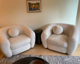 Overview of a pair of chairs, rug, table and art all included in the sale.