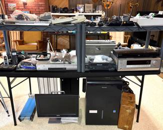 A DVD player, a computer keyboard, cameras, cords, computer monitor. 