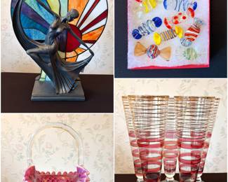 An Art Deco-style dancing lady lamp, featuring a bronze-colored resin base and a multicolored stained-glass shade in a Tiffany style, a vintage Fenton Cranberry Opalescent Hobnail glass basket with a clear handle, hand-blown Murano-style art glass candies, and a set of Art deco Pilsner glasses. 