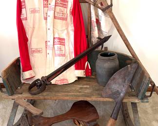 A vintage Conestoga wagon jack, an antique cast iron hay harpoon spear, vintage American stoneware pottery matte glaze crock, men’s shirt made from repurposed Hornady Magnum Shot bags and an Antique homemade children’s trike. 