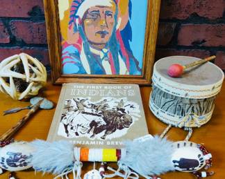 A collection of Native American-themed artifacts including a Vintage Native American paint by numbers art , a book, a 
Vintage Straight Arrow War Drum toy w/mailer-instructions-beater stick-1949 Nabisco, vintage Native American Sherman double rattle. 