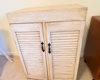 Distressed white wooden accent cabinet with louvered doors.