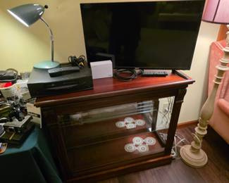 traditional-style wooden curio console or cabinet with sliding glass door.