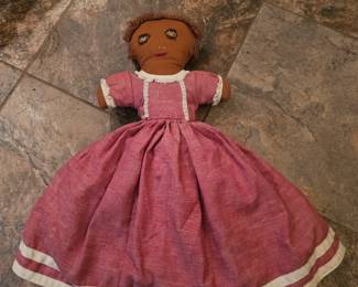 Handmade primitive cloth doll with pink dress and painted features.