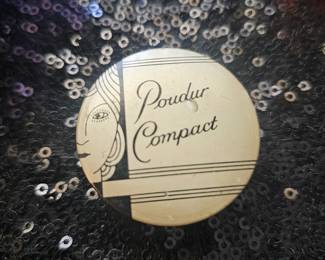 An Art Deco metal powder compact with a stylized woman's profile.