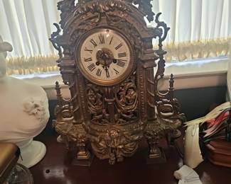 An ornate, gilded mantel clock with Roman numerals and decorative motifs.