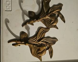 A pair of vintage brass floral wall hooks with stylized botanical designs.