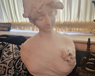 A classical plaster bust of a young woman with decorative curls.