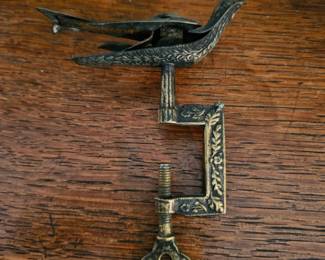 A decorative brass Victorian sewing bird with a clamp and key.