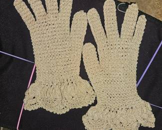 A pair of vintage beige crochet lace gloves with ruffled cuffs.