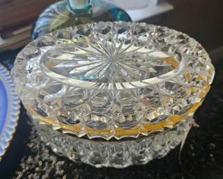 An oval cut crystal trinket box with brass trim.
