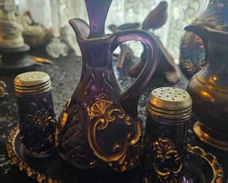 An amethyst glass cruet set with gold accents, likely by Riverside Glass Works.