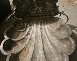 Ornate cast metal shell-shaped wall fountain basin with a decorative backplate.