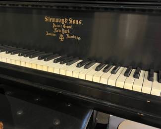 Vintage Steinway & Sons upright piano with black lacquer finish and classic ivory-style keys. Features the iconic Steinway & Sons New York branding on the fallboard. Shows age-related wear consistent with use. A distinguished instrument suitable for players, collectors, or studio décor.